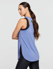 Woman wearing a blue tank top with black trim on a light gray background