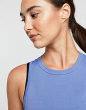 Woman wearing a blue athletic top against a white background