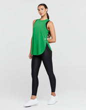 Woman wearing a green sleeveless top and black leggings on a white background