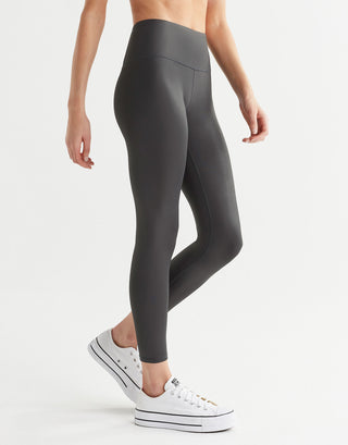 A pair of high shine gunmetal colored leggings, featuring minimal seaming and a logo at the center back. 