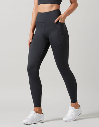 Person wearing black leggings and white sneakers on a light gray background