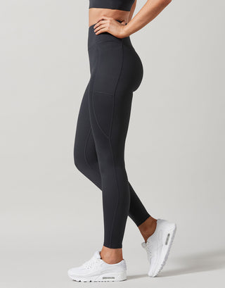 Person wearing black leggings and white sneakers on a light gray background