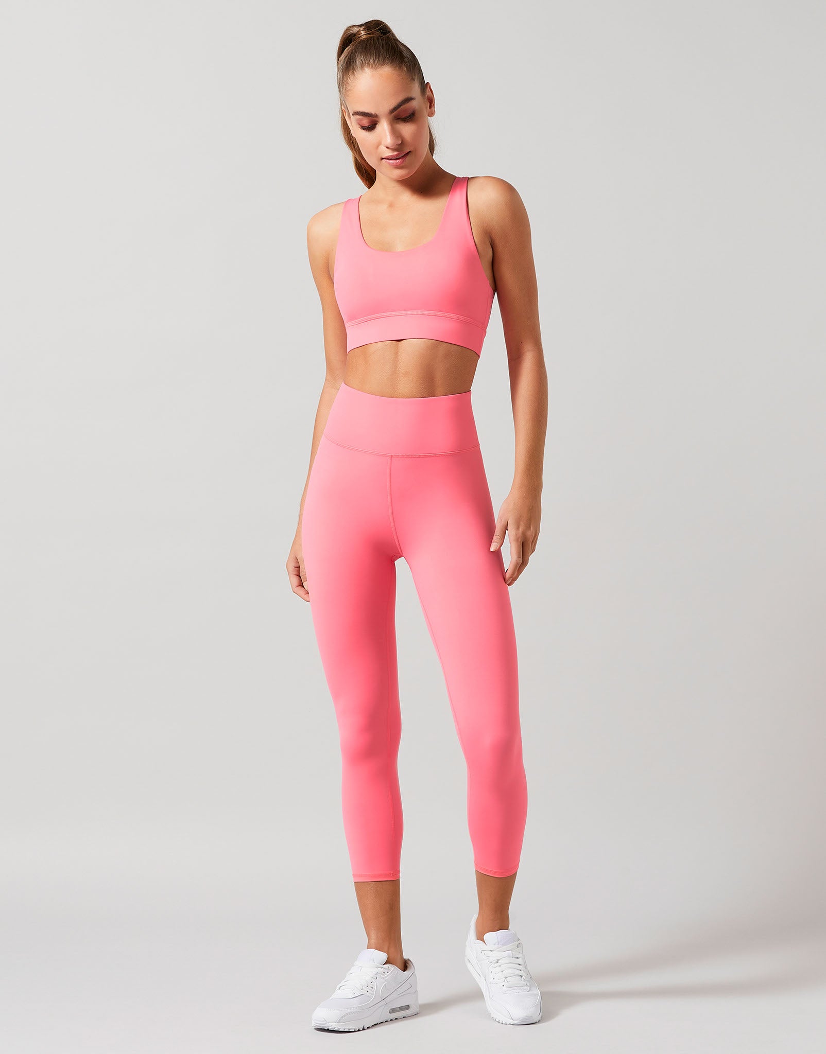 Woman wearing a pink activewear set with a grey background