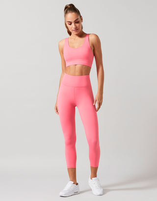 Woman wearing a pink activewear set with a grey background