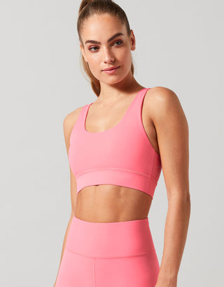 Woman wearing a pink sports bra with a grey backgound