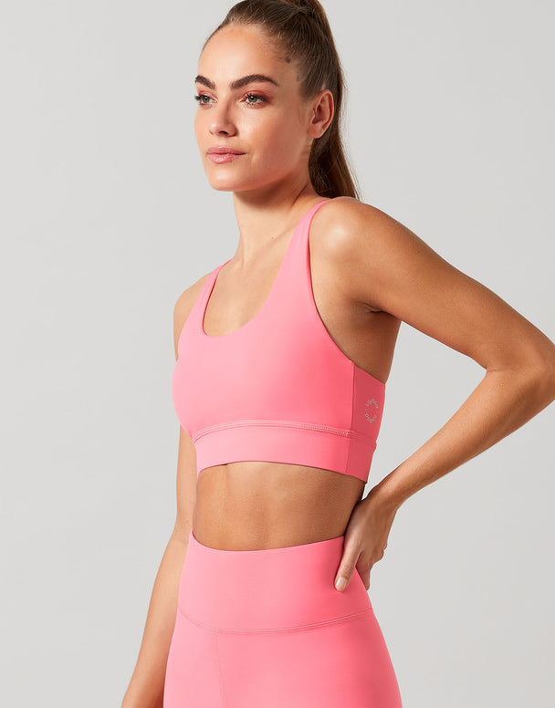 Woman wearing a pink sports bra with a grey background