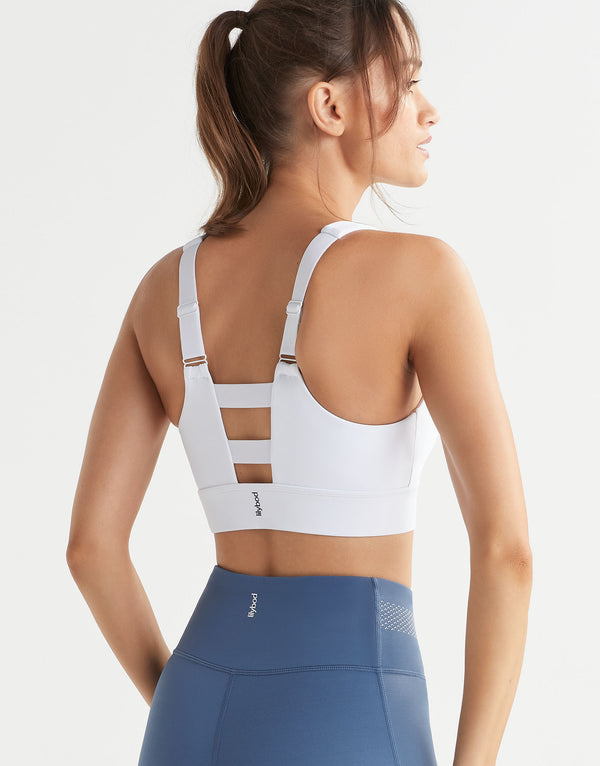 A woman wearing a white adjustable sports bra and blue leggings on a white background