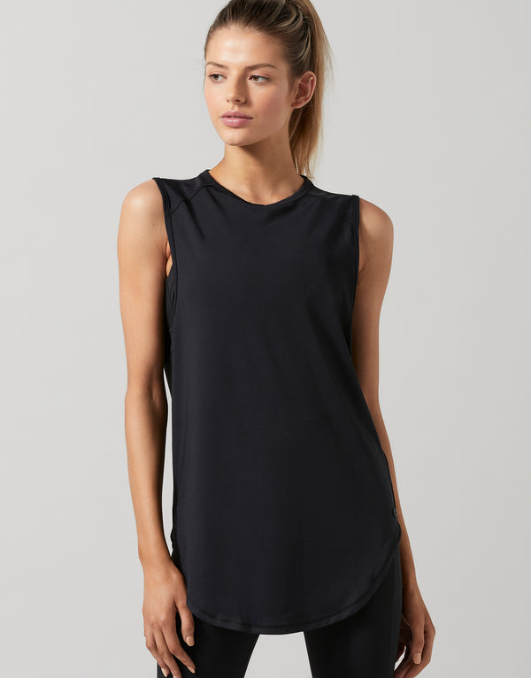 Woman wearing a black sleeveless top against a plain background