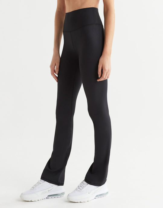A woman wearing a pair of high-waisted black bootcut leggings, shown from the waist down with a focus on the fit and design of the leggings.
