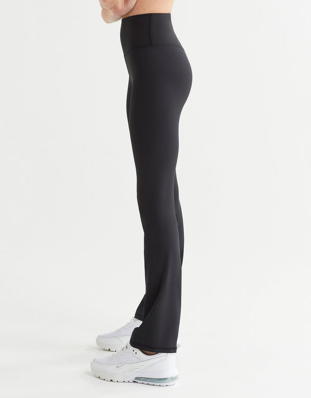 A pair of high-waisted black bootcut leggings, shown from the waist down with a focus on the fit and design of the leggings worn by a woman.