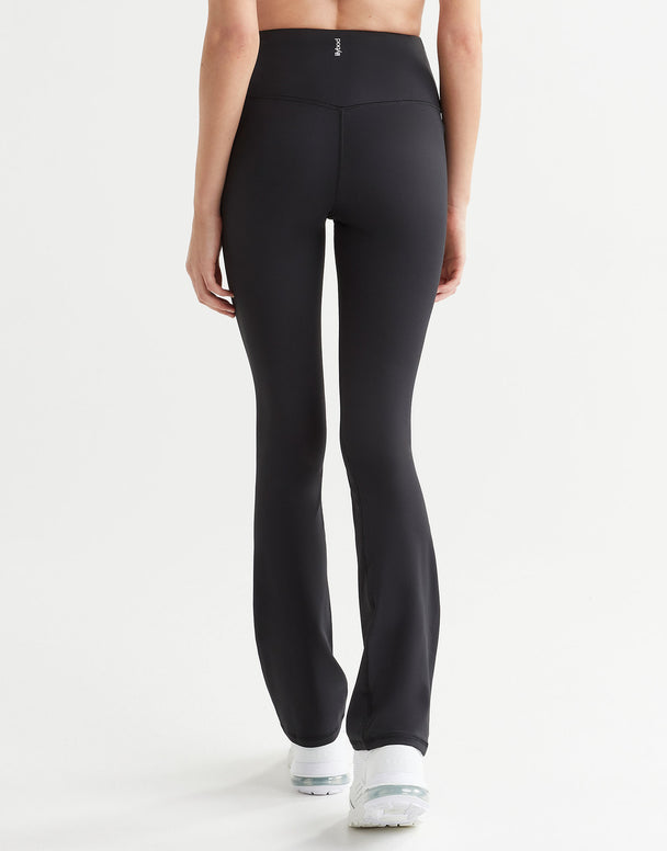 A woman in a pair of high-waisted black bootcut leggings, shown from the waist down with a focus on the fit and design of the leggings.