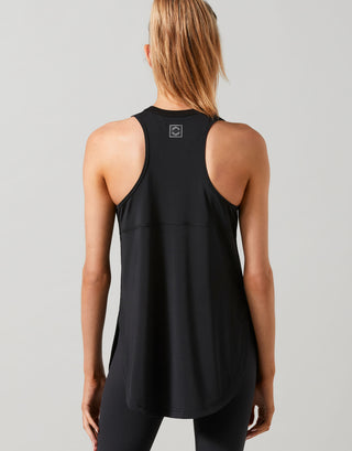 A woman wearing a black Lilybod Zela Mesh Tank Top with a wide scoop neck and racer back, paired with black leggings.