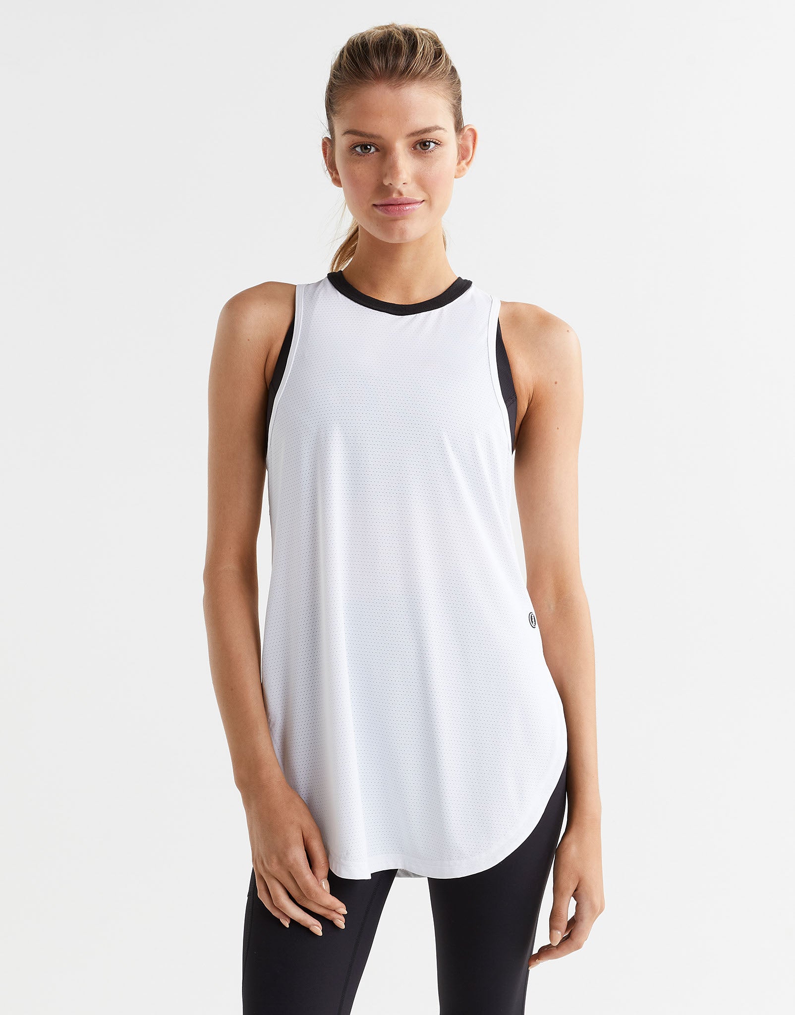 Woman wearing a white sleeveless top with black trim on a white background