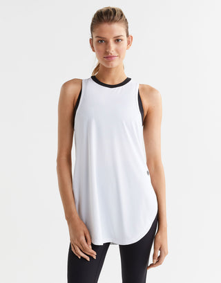 Woman wearing a white sleeveless top with black trim on a white background