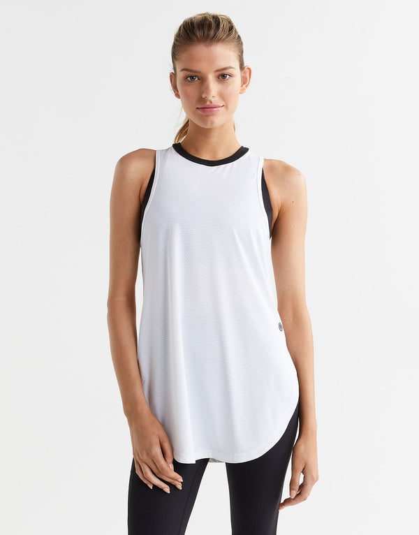 Woman wearing a white sleeveless top with black trim on a white background