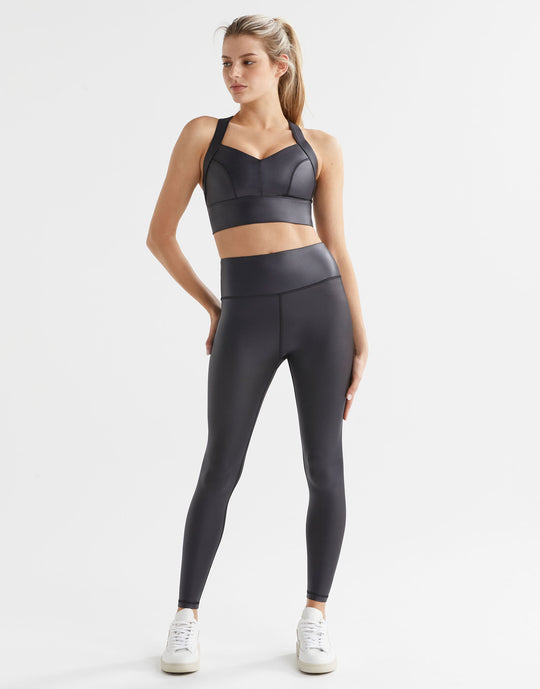 Woman wearing high shine black athletic leggings and a matching sports bra