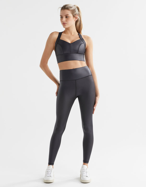 Woman wearing high shine black athletic leggings and a matching sports bra