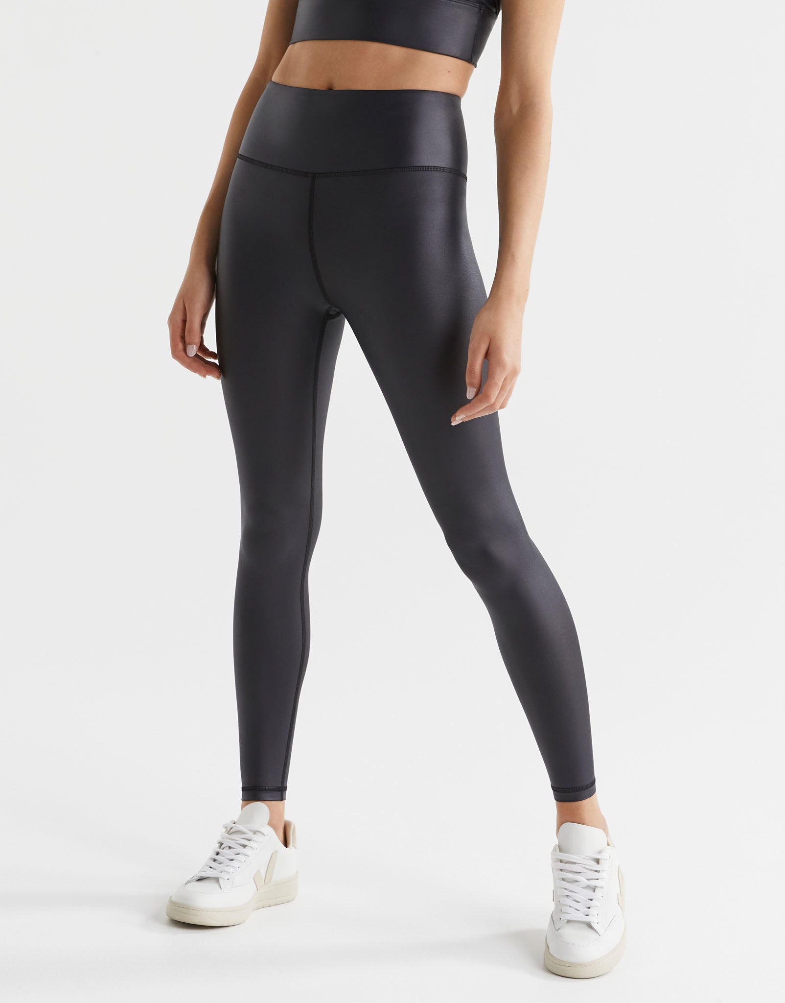 Woman wearing high shine black athletic leggings and white trainers