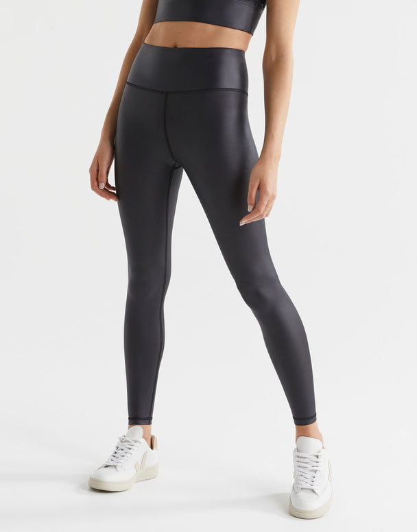 Woman wearing high shine black athletic leggings and white trainers