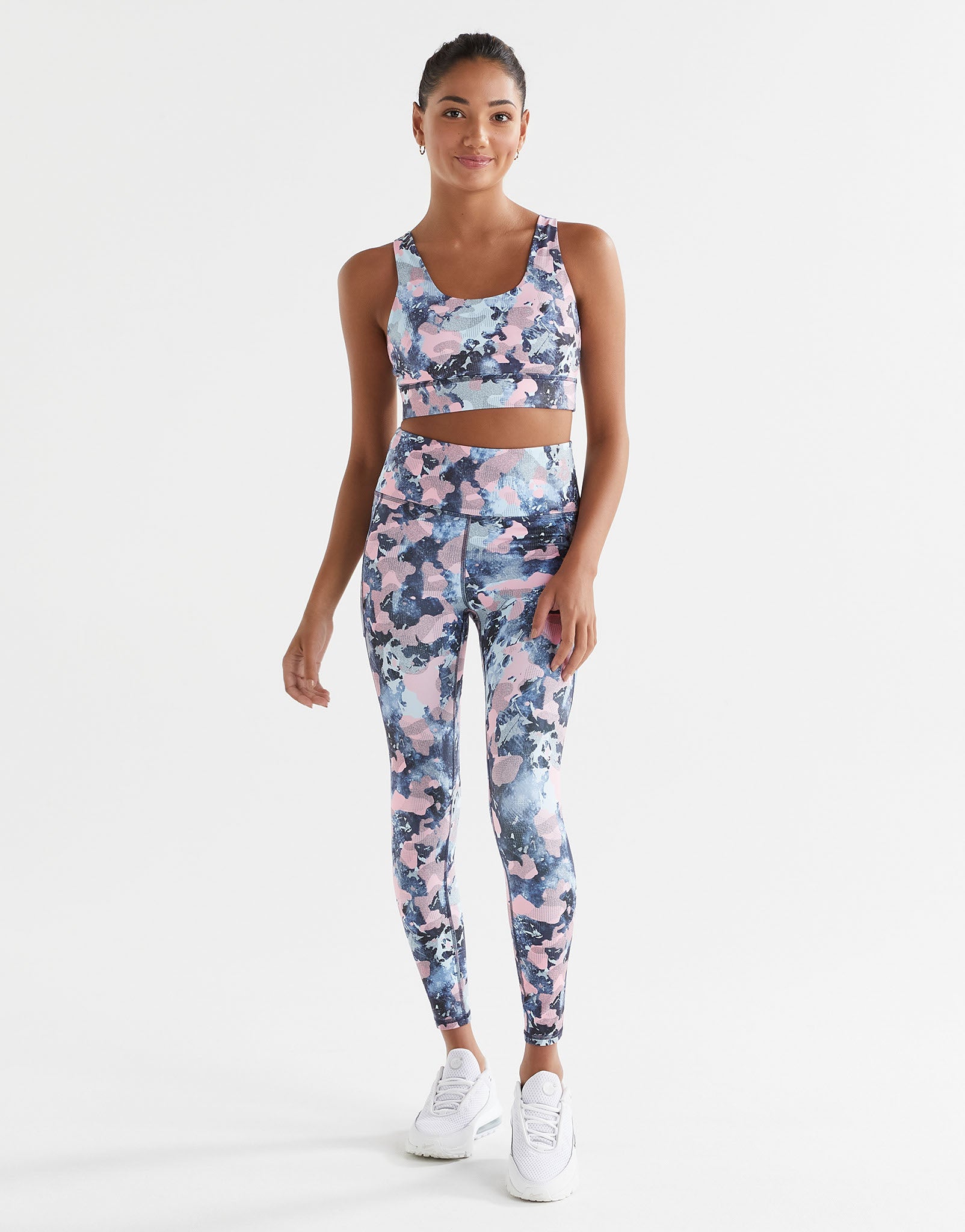 A woman wearing a blue and pink activewear set on a white background