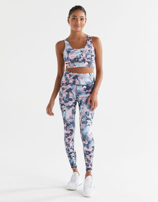 A woman wearing a blue and pink activewear set on a white background