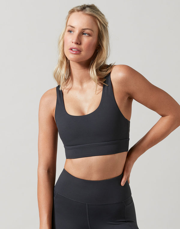 Woman wearing a black sports bra and leggings on a light gray background