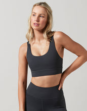 Woman wearing a black sports bra and leggings on a light gray background