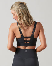 Woman wearing a black sports bra and leggings on a gray background