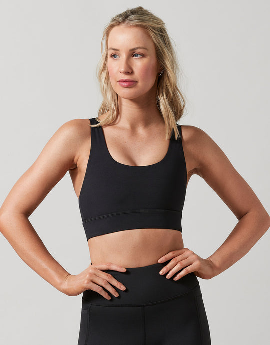 Woman wearing a black sports bra and leggings on a plain background