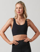 Woman wearing a black sports bra and leggings on a plain background