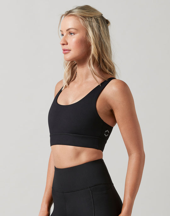 Woman wearing a black sports bra and leggings on a light gray background