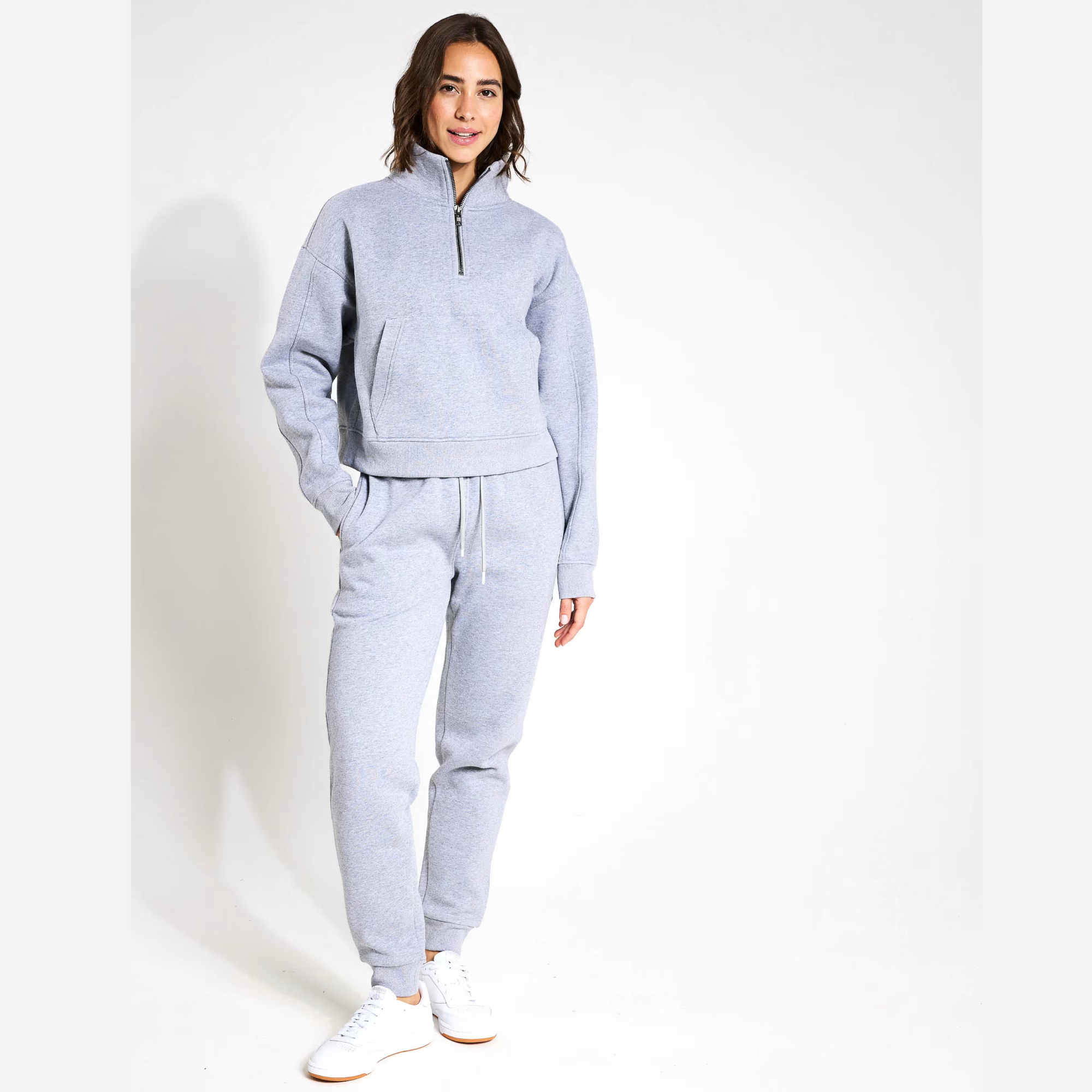 Woman wearing a grey tracksuit on a white background