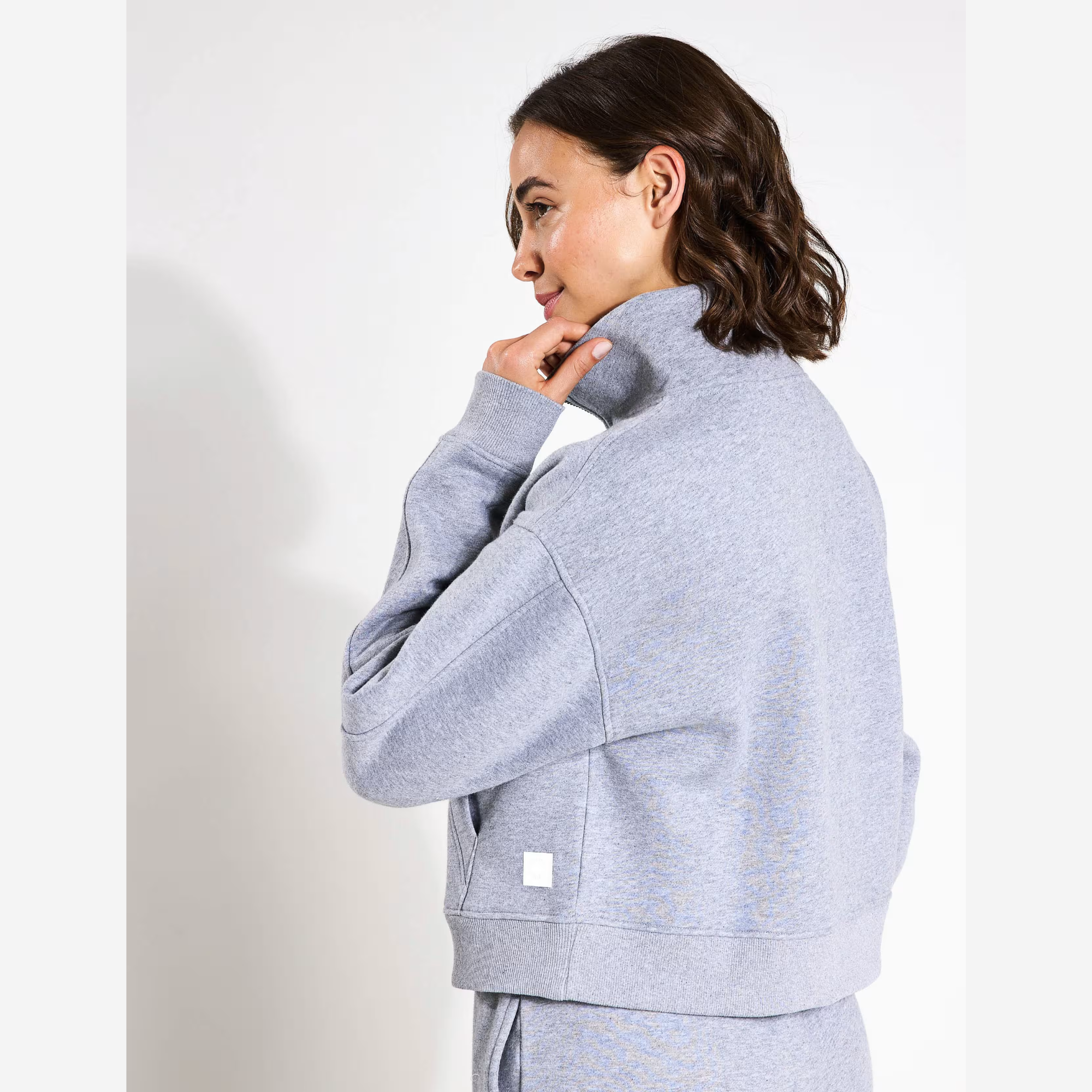 Woman wearing a grey tracksuit against a white background