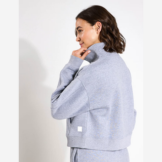 Woman wearing a grey tracksuit against a white background