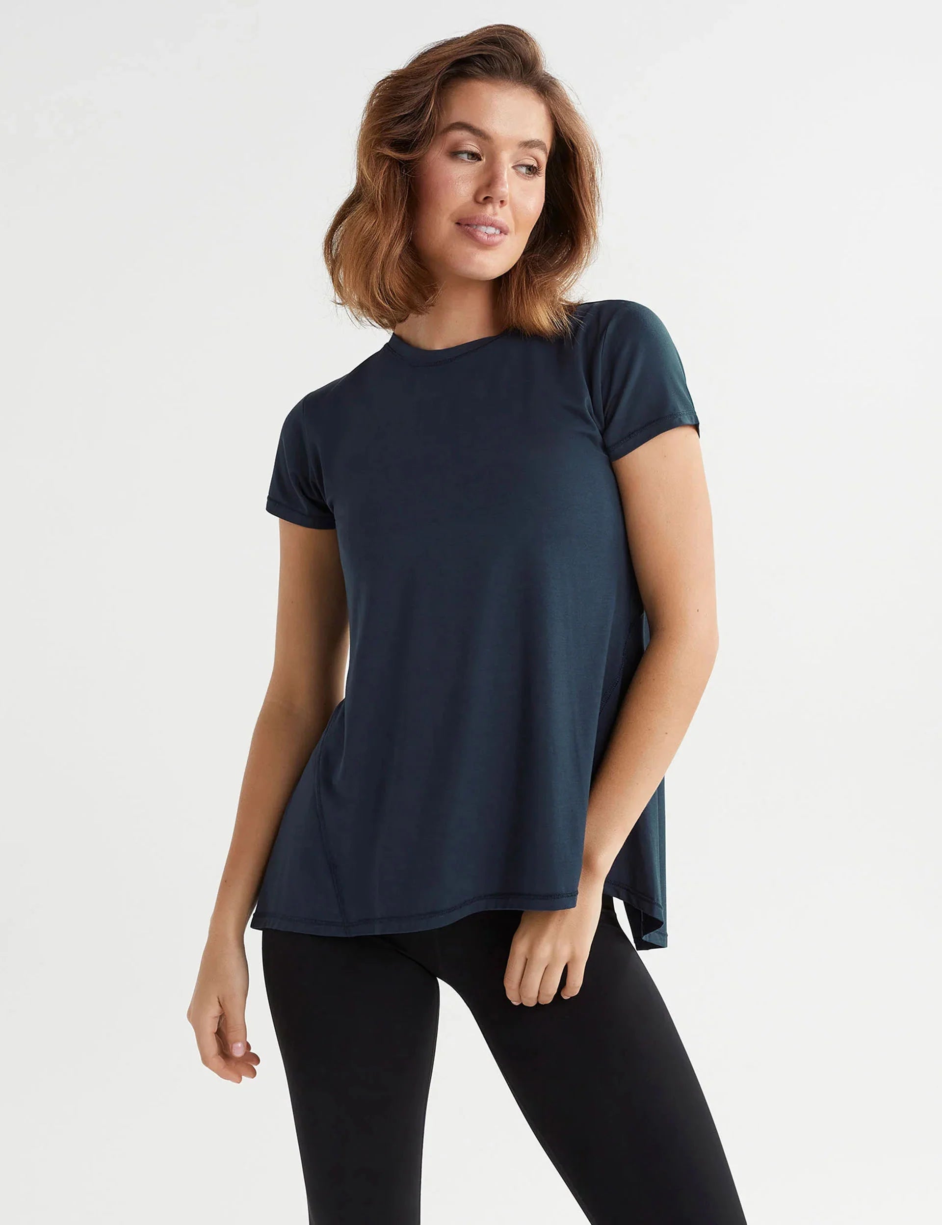 Woman wearing a navy blue t-shirt and black leggings on a white background