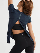 Person wearing a navy blue top and black leggings on a white background