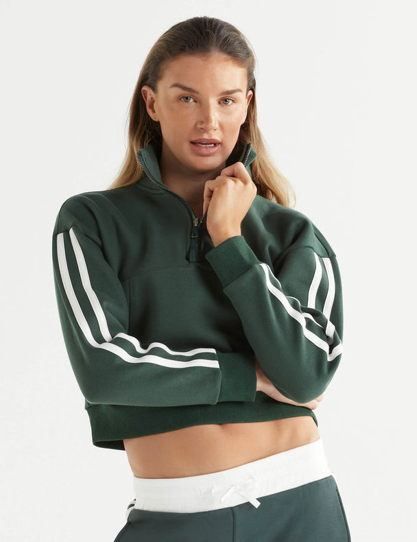 Woman wearing a green sweatshirt with white stripes on a plain background