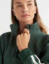 Woman wearing a green jacket with a white stripe on a light background
