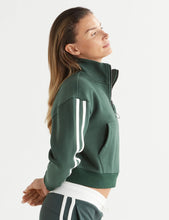 Woman wearing a green tracksuit with white stripes on a white background