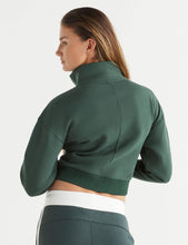 Woman wearing a green athletic jacket on a white background